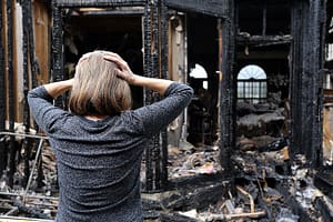 female looking in despair at a burnt down home